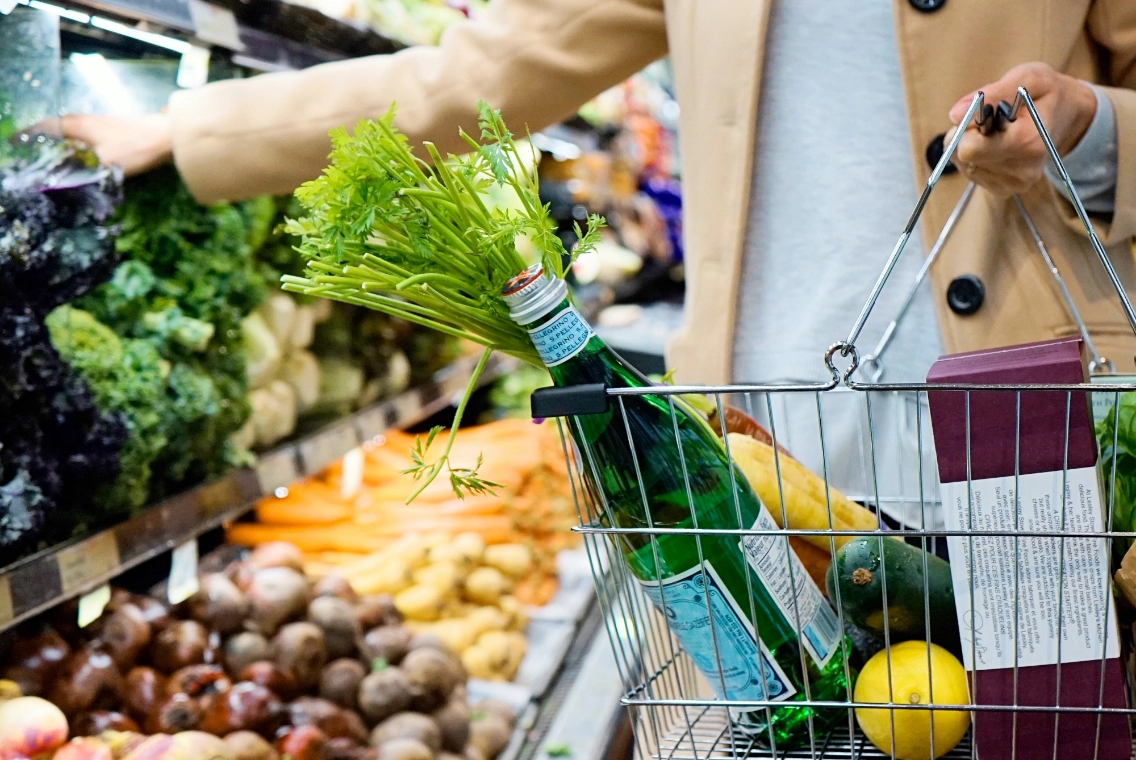 a shopping cart with a bottle and vegetables